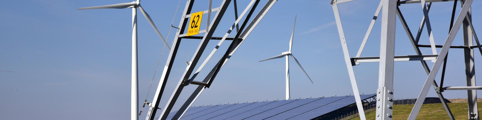 Foto van windmolens, zonnepanelen en een elektriciteitsmast