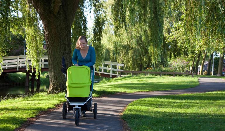 vrouw in park met kinderwagen