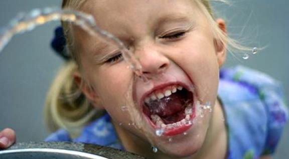 meisje drinkt uit kraan; water kan lood en nikkel bevatten